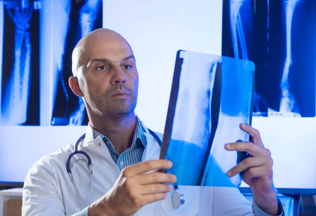 A male orthopedic doctor is examining X-rays.
