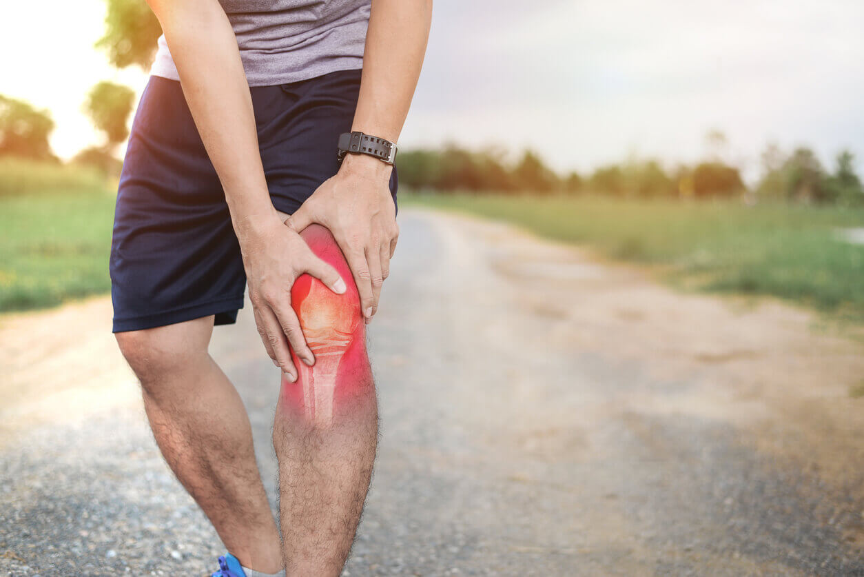 Man on a jog outside experiencing a knee injury he needs treatment for.