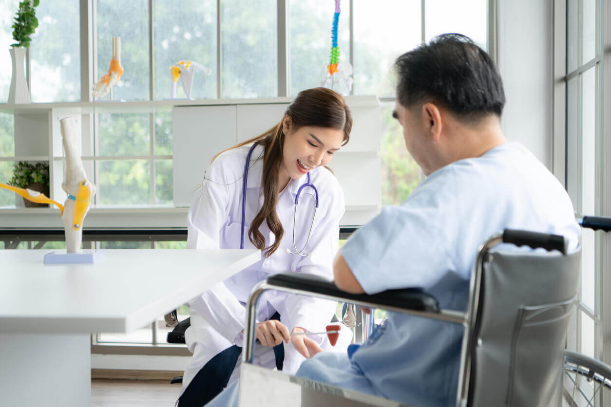 A female orthopedic surgeon uses a reflex hammer on a senior patient.